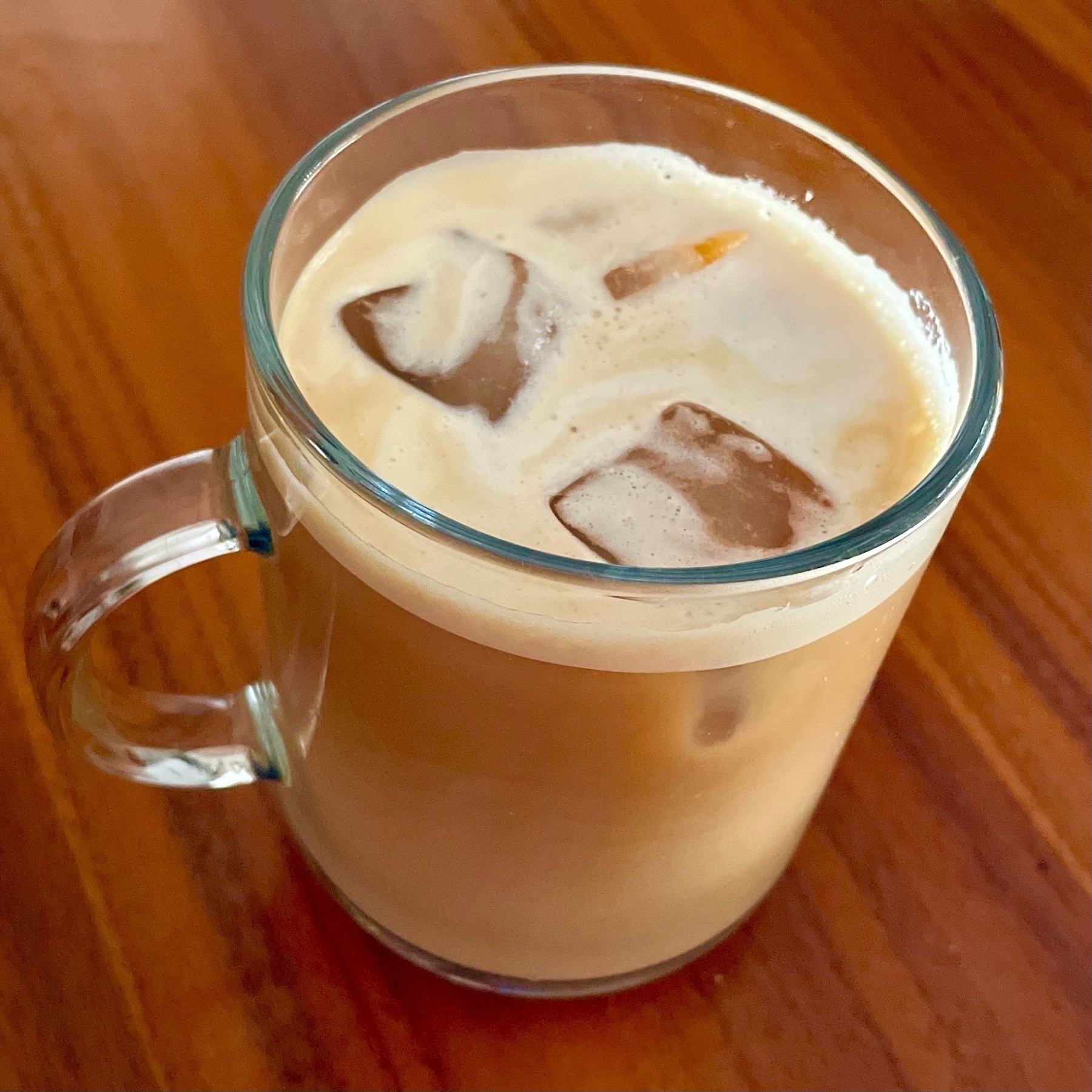 Cold milk cappuccino with ice in a transparent mug